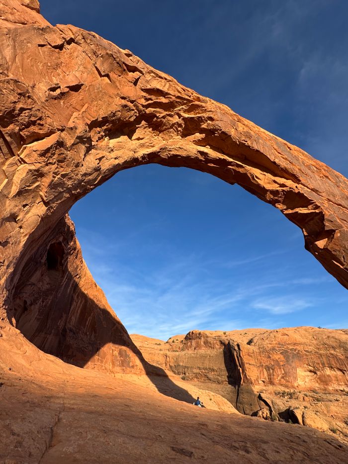 Dramatic view of a natural sandstone arch in Moab, Utah against a bright blue sky.